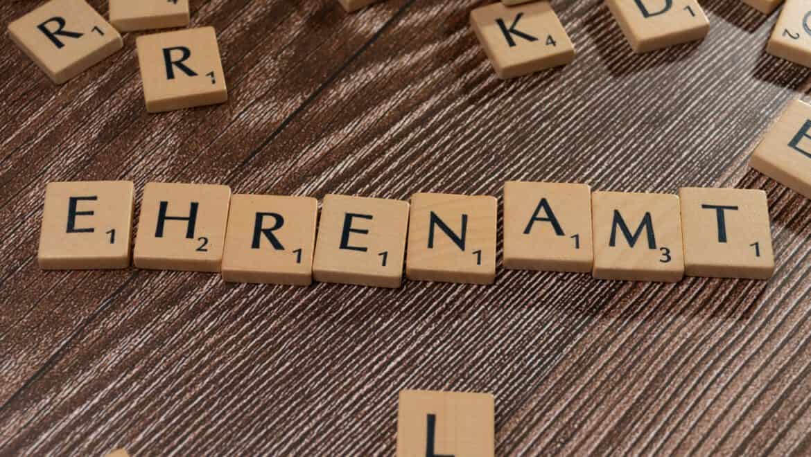 Scrabble-Steine mit dem Wort 'Ehrenamt' auf Holzoberfläche.